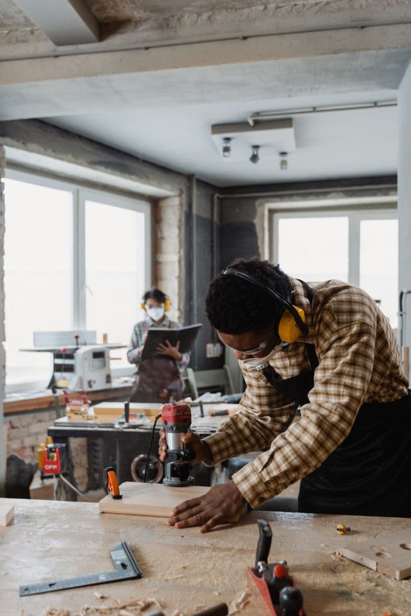 A carpenter wearing eye and ear protection while working with wood